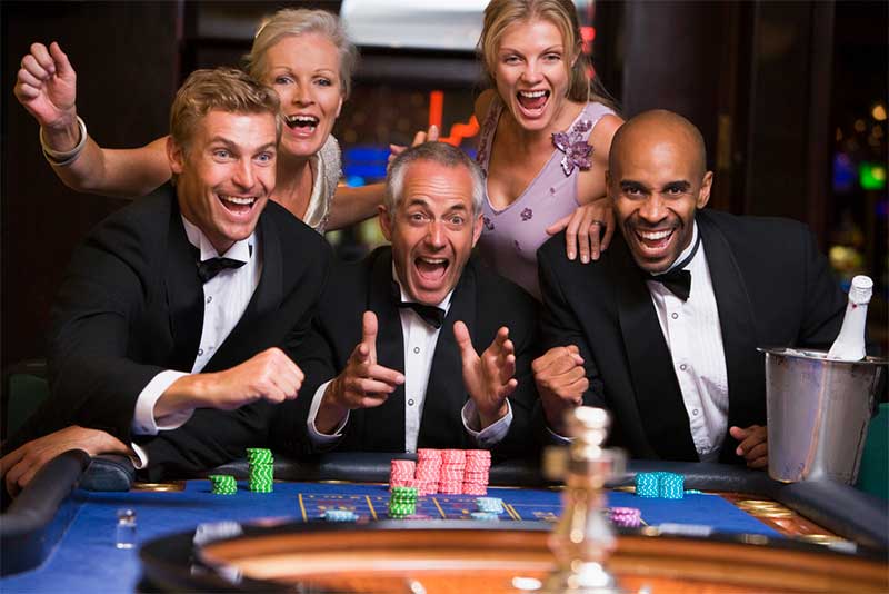 Group of friends celebrating at roulette table in casino